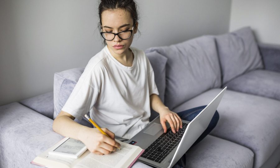 woman-with-laptop-making-notes-book